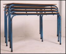 A set of 4 retro 20th century school stacking tables raised on painted metal tubular supports with