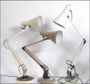 A collection of three Herbert Terry anglepoise desk lamps raised on circular bases,