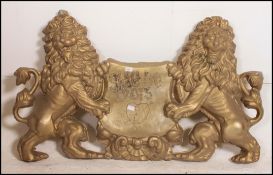 A cast plastic armorial double lion crested gilded shop - advertising sign being filled to verso