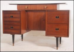 A 1970's retro teak wood dressing table desk raised on shaped legs with suspension set desk top.