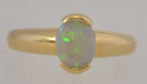 An 18ct gold and opal ladies ring. The buckle style setting with oval opal stone to centre.
