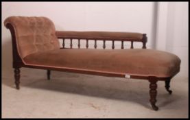 A Victorian oak chaise longue with carved scrolling head rest, open arm spindle back,
