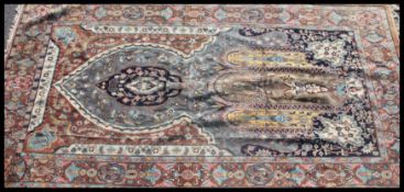 A handmade Hereke rug with central Mihrab having tassled ends with blue yellow and ochre red ground.