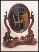 A stunning 19th century mahogany toilet swing mirror having scroll supports on a serpentine base