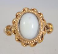 A 9ct gold ring hallmarked London with a white cabochon stone in a rope twist setting. Size N.