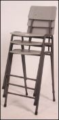 A stack of vintage 1980's retro science laboratory school stools with grey vinyl seats on tubular
