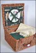 A collection of vintage linens and cloths all being contained within a vintage whicker picnic