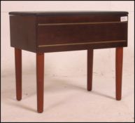 A 1970's retro teak sewing box raised on tapered turned legs with vinyl upholstered hinged top to