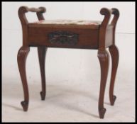 An Edwardian mahogany piano stool raised on slender legs with hinged seat and shaped handle sides.
