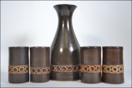 A jersey pottery carafe and four matching beakers, each with a continual geometric band,