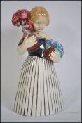 An early 20th century wiener werkstätte ceramic figurine of a girl holding flowers.