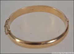 A hallmarked 9ct gold bangle bracelet. Hallmarked for Birmingham , maker L and Co. Weight 17.7g.