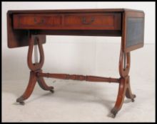 A Regency style leather top mahogany drop leaf desk raised on lyre shaped supports with tooled
