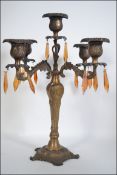 An early 20th century five point brass candelabra having scroll work decoration adorned with amber