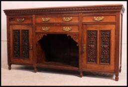 An Edwardian walnut sideboard with three upper drawers above two large hinged doors with carved