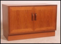 A 1970's retro low G-Plan teak wood side cabinet raised on inset plinth base with cupboards above