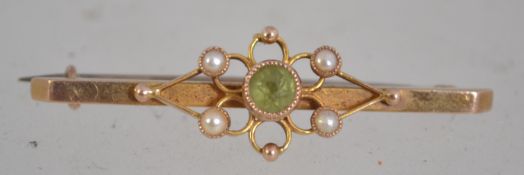 A 15ct gold and peridot set ladies bar brooch with seed pearl borders having pin to verso.
