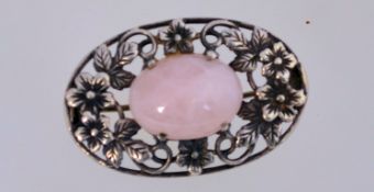 A 1920s silver and rose-quartz brooch with a rose-quartz cabochou in a floral setting,