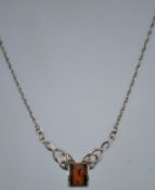 A silver and amber celtic style necklace with a lobster claw clasp.
