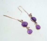 A pair of unmarked silver and amethyst cabochon earrings, measuring 4cms long including hooks.
