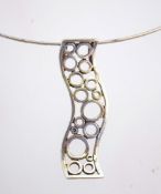 A silver tone necklace with a large pendant, marked 