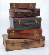 A stack of 5 vintage suitcases to include leather and canvas examples all of graduating sizes.
