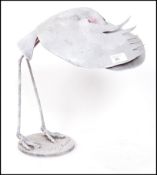 A cast metal sculpture study of an African umbrella bird being signed by the artist to the base.