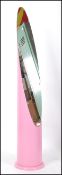 A large unusual pink lipstick mirror. Floorstanding of conical form with mirror sectional top.