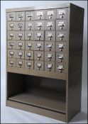 A vintage 20th century Industrial 36 drawer metal filing cabinet in beige raised over open arcade