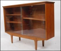 A 1970's retro G-Plan teak bookcase cabinet raised on tapered legs with drawers underneath a