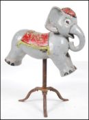 A vintage mid century fairground ride - childs size elephant ride being raised on a later tripod