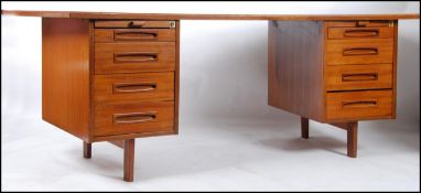 A 1970's large Danish influence teak wood desk having shaped supports with raised pedestals having