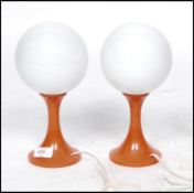 A pair of 1970's retro orange and white globe glass table lamps.