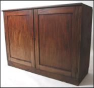 A large early 20th century mahogany school cupboard raised on a plinth base with double door