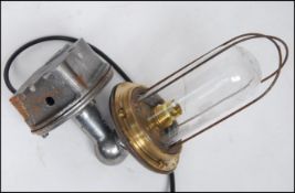 An Industrial cast metal heavy set bulkhead / dairy lamp with caged pendant style bulb on polished