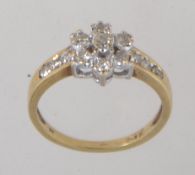 A 9ct gold and diamond ring with central diamond cluster and channel set diamond shoulders.