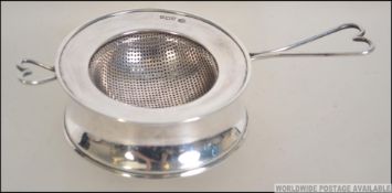 A silver hallmarked tea strainer with heart shaped handle Birmingham assay marks together with a
