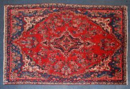 A 20th century Persian rug with red ground having floral design around a central medallion with
