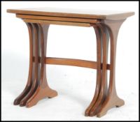 A 1970's G-Plan teak wood nest of tables raised on shaped supports with bow stretchers to each