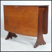 A 1970's teak wood drop leaf Danish influence dining table being raised on splayed legs with drop