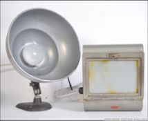 A vintage heat lamp converted to a desk lamp raised on a cast metal base with a polished metal