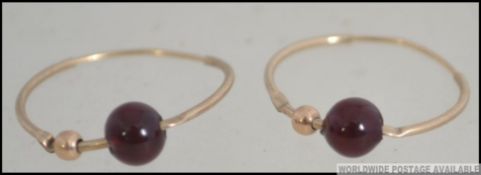 A pair of 9ct gold and ruby garnet glass stone bead adorned earrings. Total weight 0.8g.