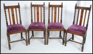 A set of four Edwardian oak dining chairs having barley twist uprights overstuffed seat pads raised