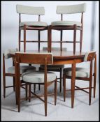 A mid-20th century G-Plan teak circular pull out extending dining table with a single additional