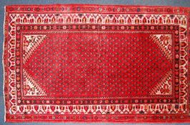 A 20th century Persian rug with unusual multiple medallion design on red ground with decorative