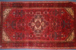 A 20th century handwoven Persian rug with central medallion and decoration with decorated borders.