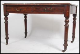 A large Victorian mahogany writing table desk being raised on turned legs with twin frieze drawers