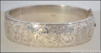 A heavy silver hallmarked ladies rococo bangle being chase decorated complete with the safety chain.