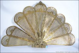 A 20th Century brass metamorphic peacock firescreen having eight fan out leaves with a Griffin base.
