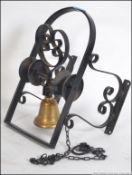 A retro brass wall bell being set within a wrought iron scroll work double sided wall mountable